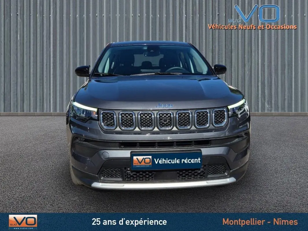 Vue frontale d'un Jeep Compass gris 2024 avec calandre distinctive et phares LED allumés.
