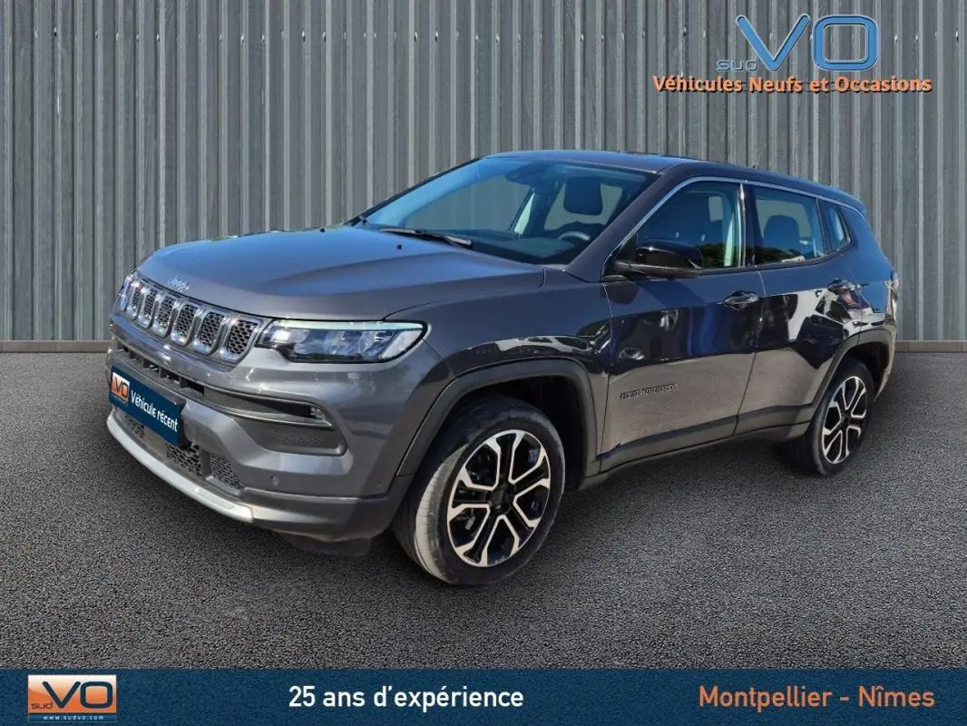 Jeep Compass gris 3/4 avant droit, jantes alliage 18 pouces, calandre distinctive et phares LED visibles.