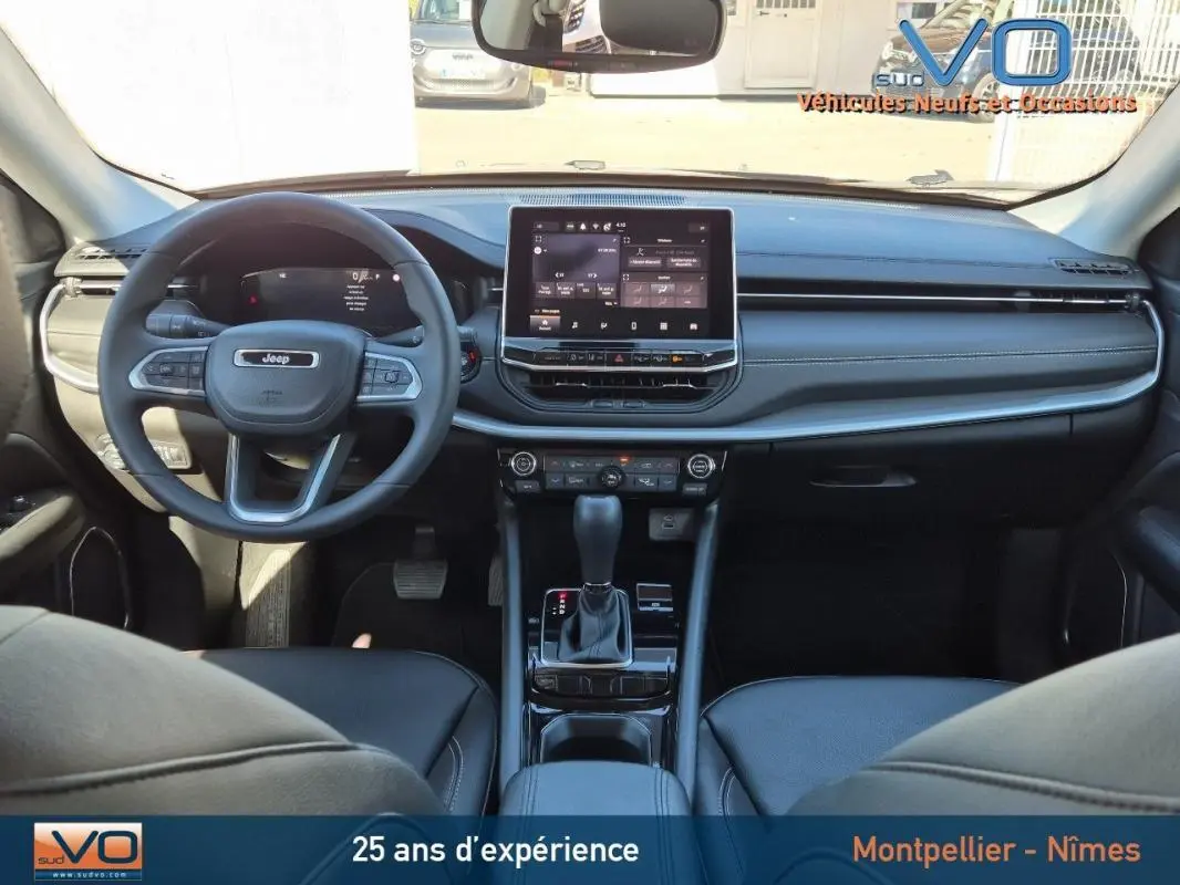 Intérieur du Jeep Compass 2024 gris, vue frontale du tableau de bord avec écran tactile et volant multifonction.