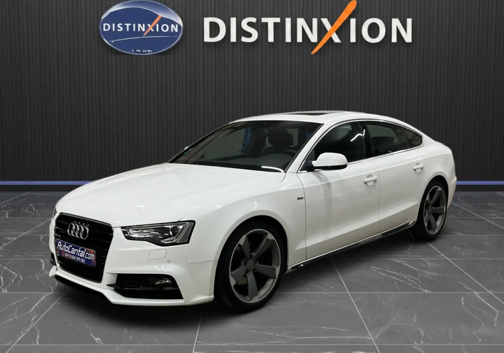 Audi A5 Sportback blanc vue 3/4 avant droit, avec jantes 5 branches foncées et calandre noire distinctive.