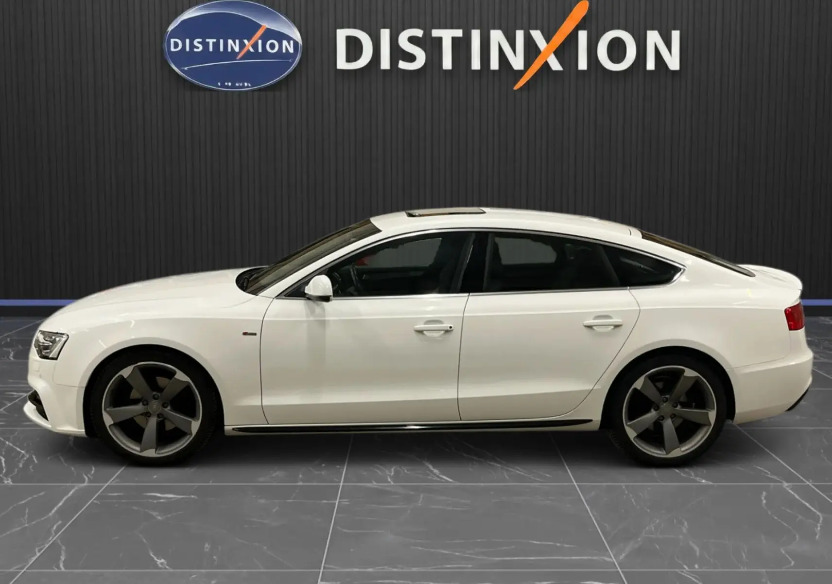 Audi A5 Sportback blanc vue de profil côté gauche, jantes 5 branches foncées et toit ouvrant panoramique.