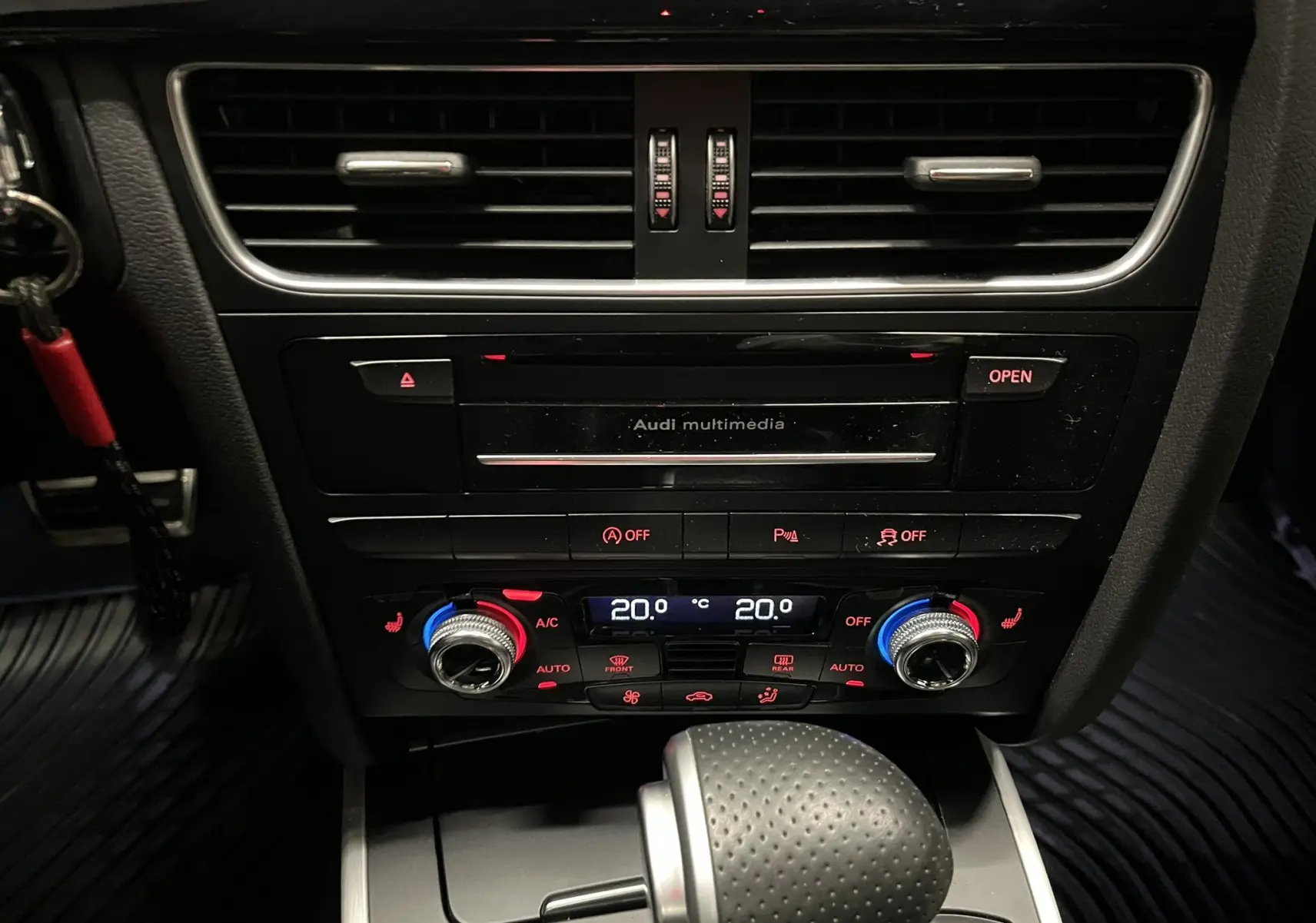 Vue rapprochée du tableau de bord central noir de l'Audi A5 Sportback avec commandes climatisation et levier de boîte auto.