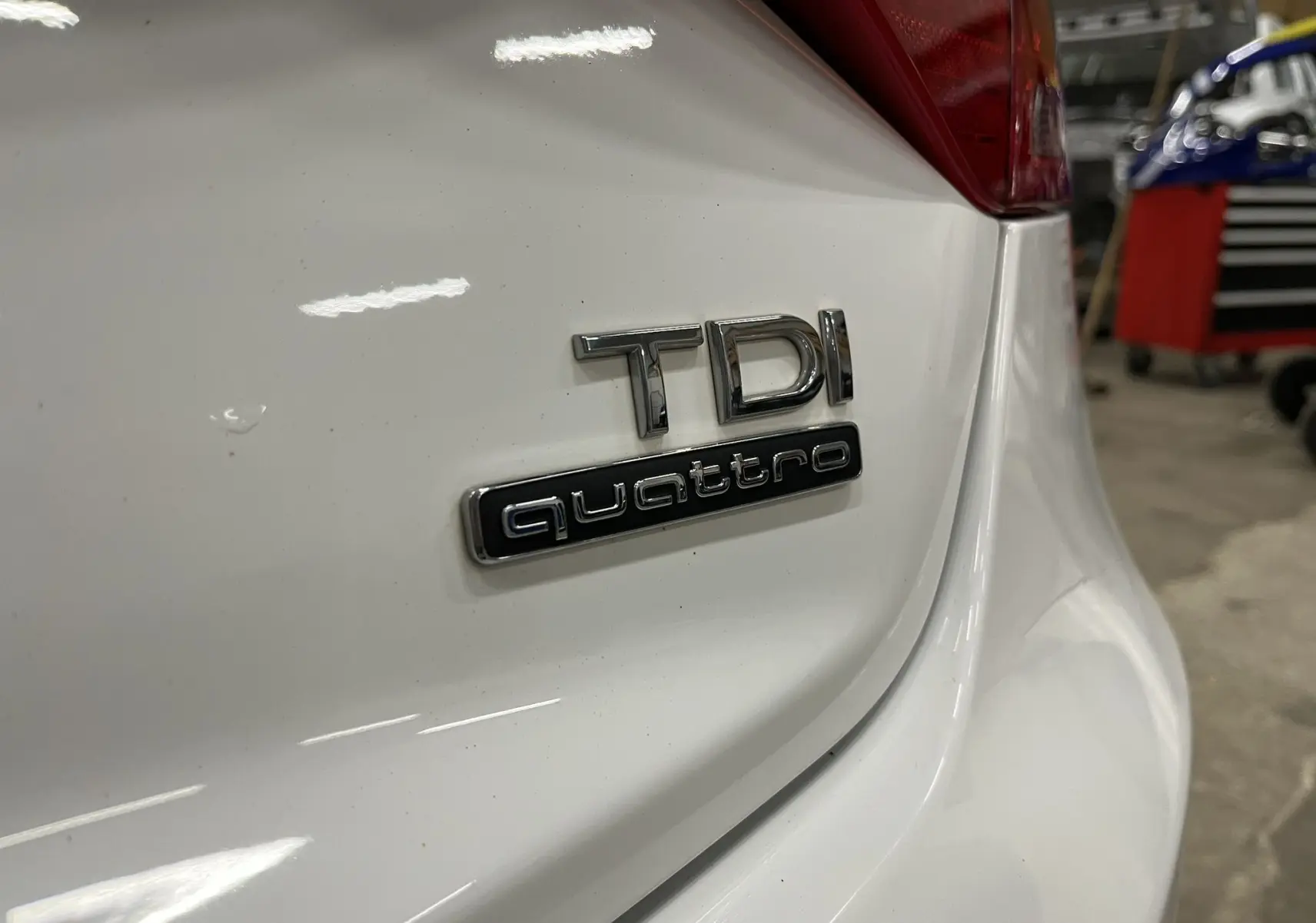 Gros plan sur l'arrière blanc d'une Audi A5 Sportback 2.0 TDI avec badges TDI et quattro visibles.