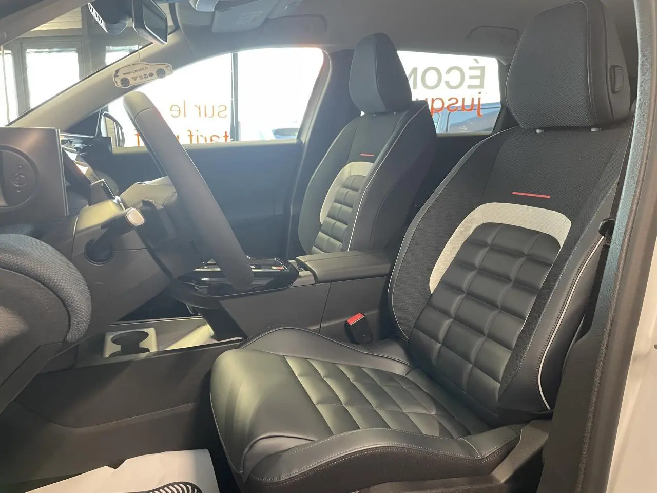 Vue intérieure côté conducteur du Citroën C5 Aircross 2026, sièges noirs avec inserts gris et rouge, volant multifonctions.