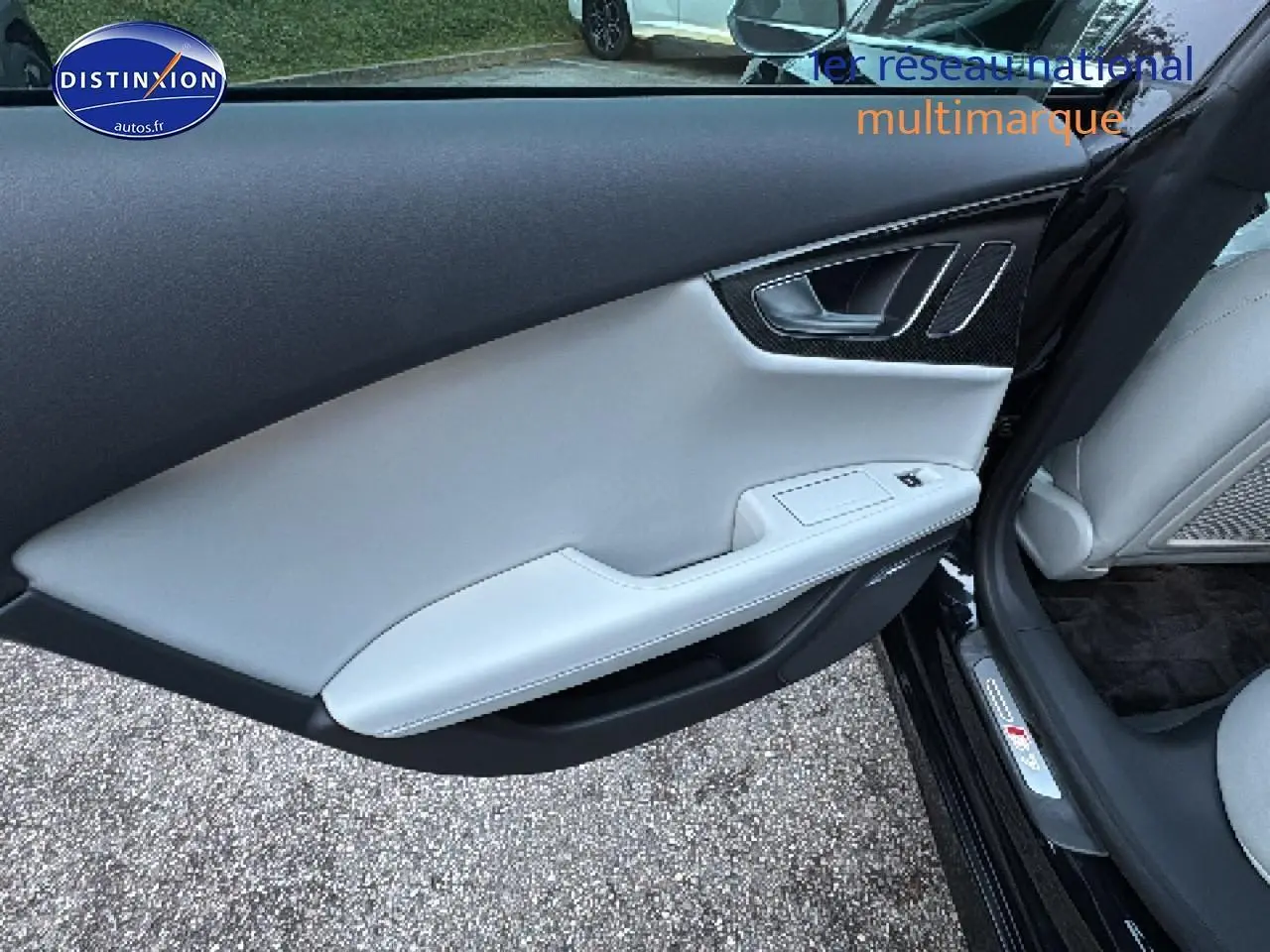 Vue intérieure côté gauche de la porte avant d’une Audi S7 Sportback noire avec garniture cuir claire et insert carbone.