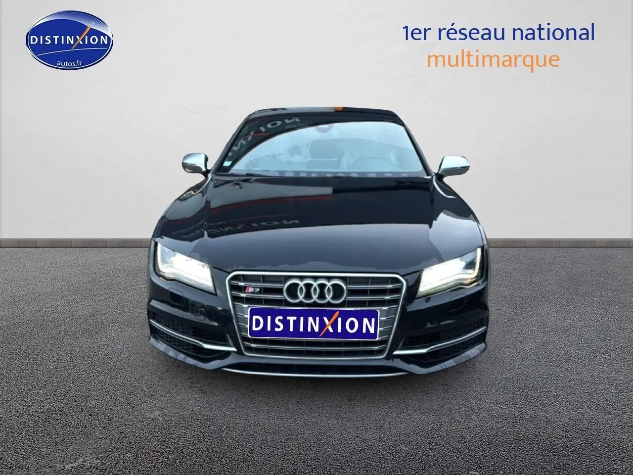 Vue de face d'une Audi S7 Sportback noire avec calandre chromée et phares allumés sur fond neutre.