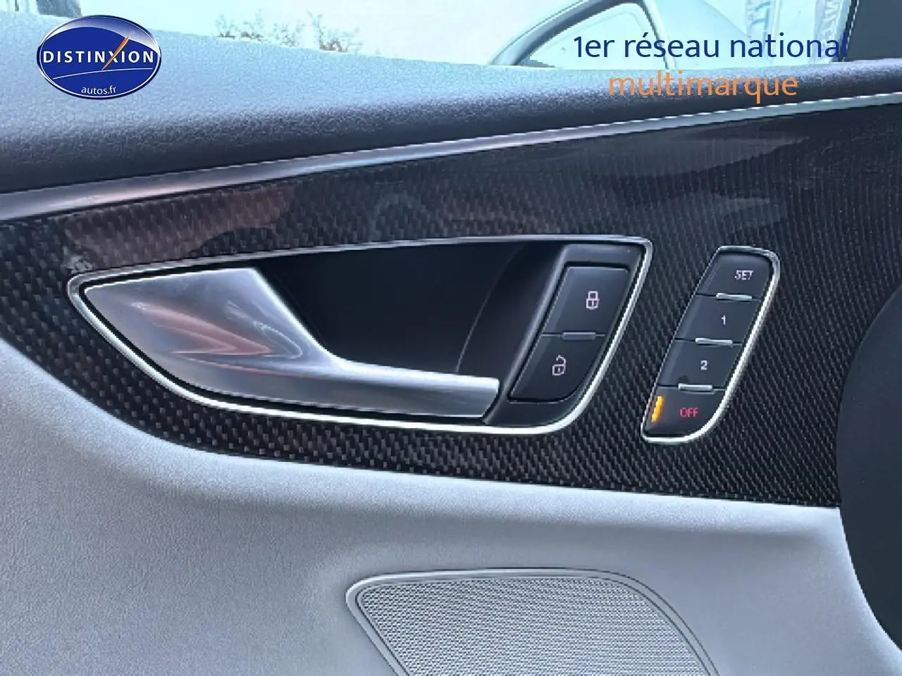 Gros plan sur la poignée intérieure côté gauche en aluminium et garniture carbone du panneau de porte gris clair d’une Audi S7 Sportback noire.