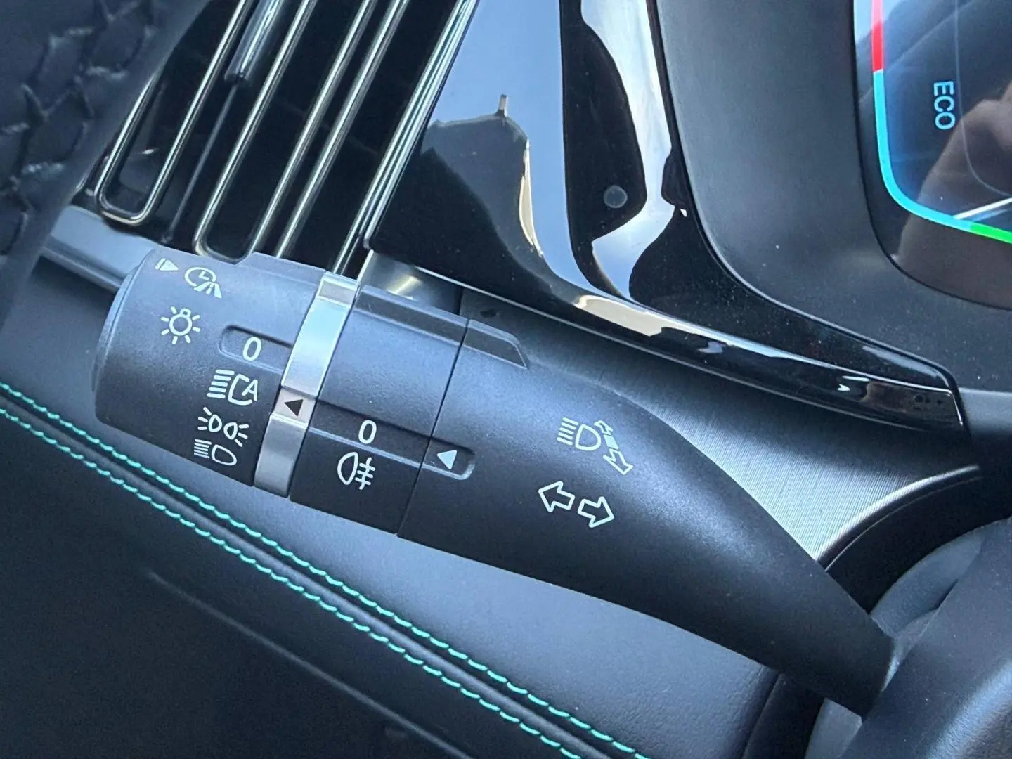 Gros plan sur la manette de clignotants et feux du tableau de bord intérieur du BYD SEAL U, finition noire avec surpiqûres vertes.