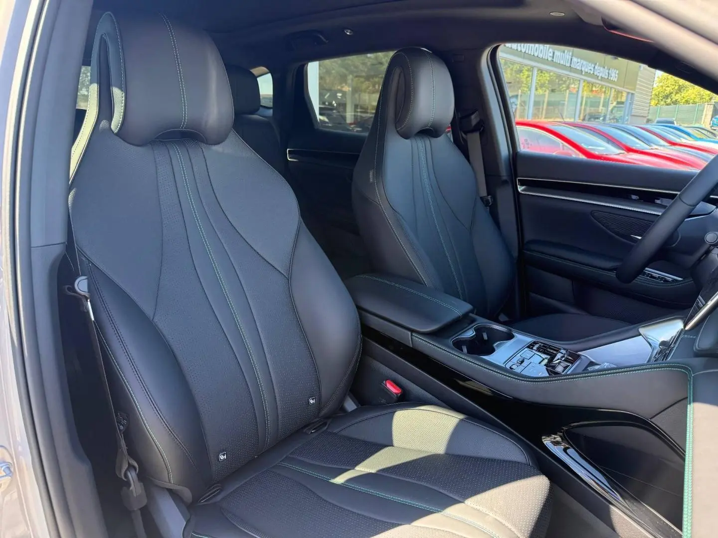Vue intérieure côté avant droit du BYD SEAL U 1.5 DM-i 324ch Design AWD avec sièges cuir noirs et surpiqûres vertes.