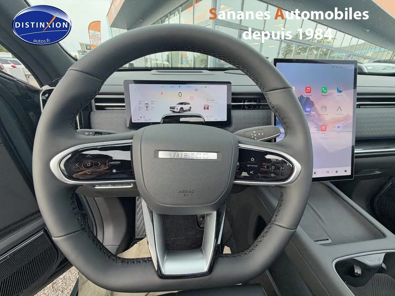 Vue intérieure centrée sur le volant du JAECOO J7 1.5 PHEV Exclusive avec tableau de bord numérique et écran tactile vertical.