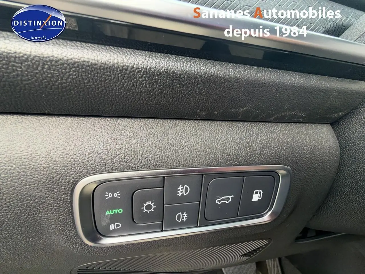 Gros plan sur les commandes d’éclairage et d’ouverture du coffre du JAECOO J7 1.5 PHEV vert olive, intérieur noir.