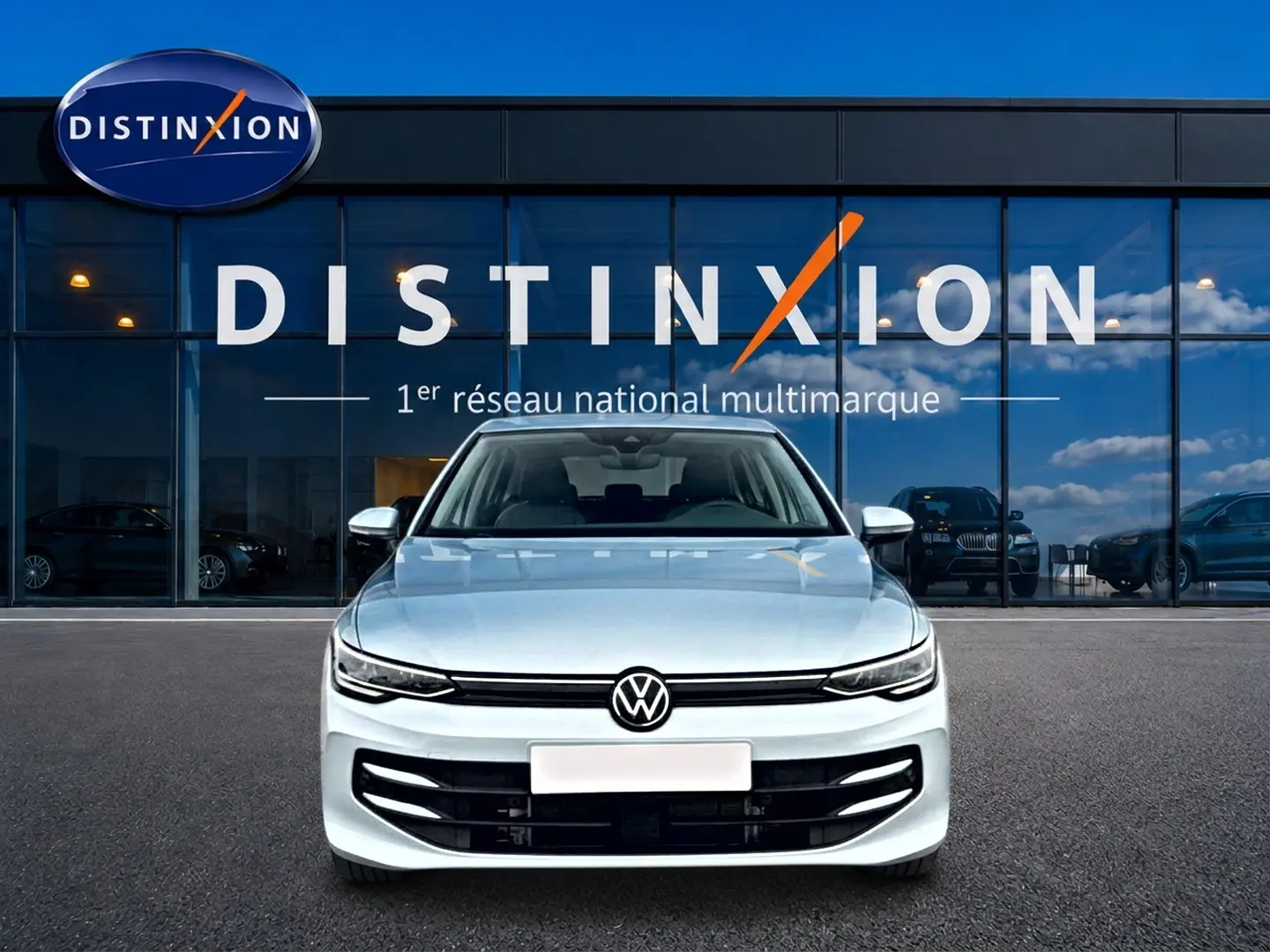 Vue frontale d'une Volkswagen Golf 1.5 etsi evo2 116 life dsg7 bleu glacier, devant une vitrine Distinxion.