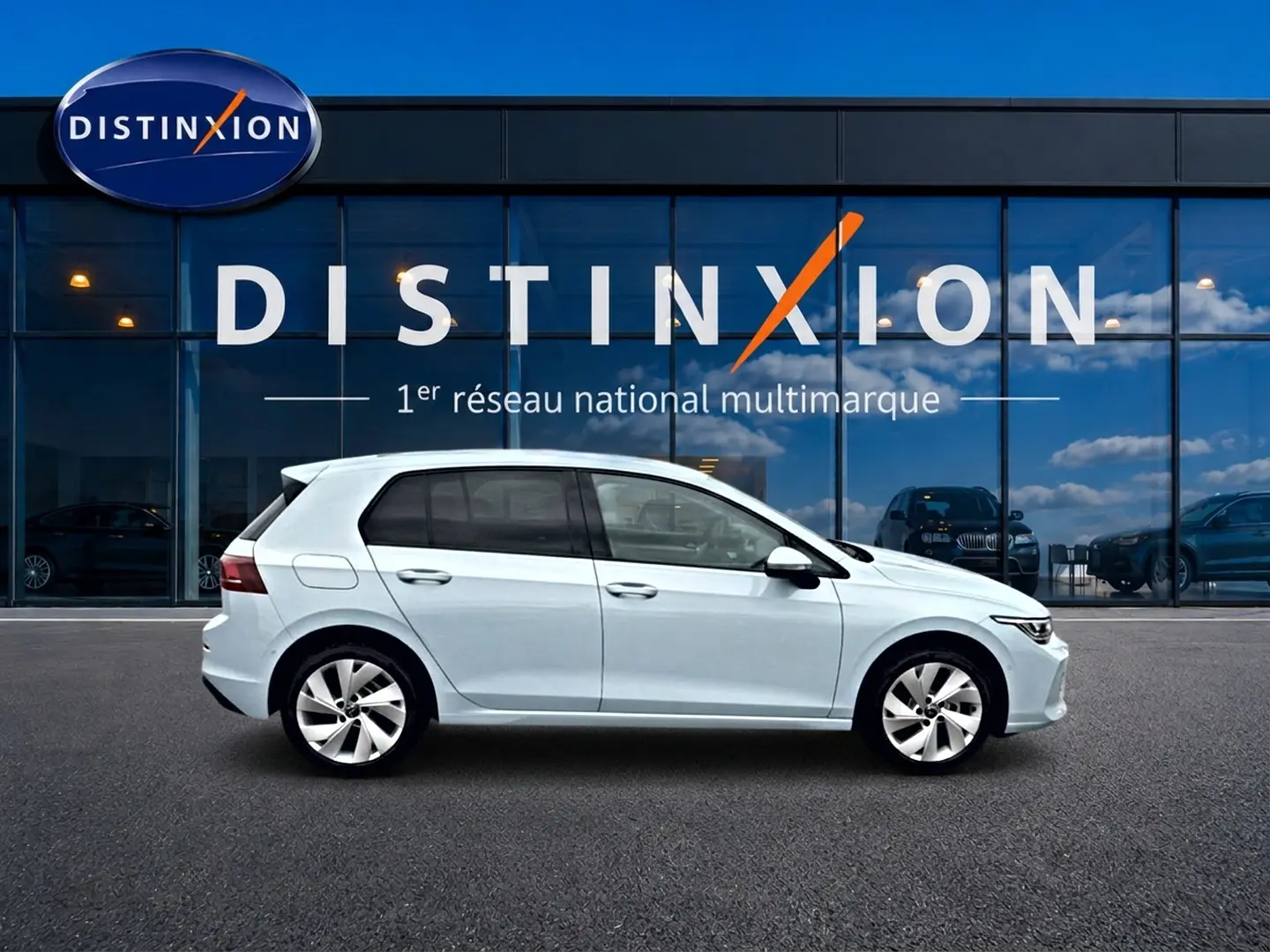 Vue latérale droite d'une Volkswagen Golf 1.5 etsi evo2 116 life dsg7 bleu glacier devant une vitrine Distinxion.