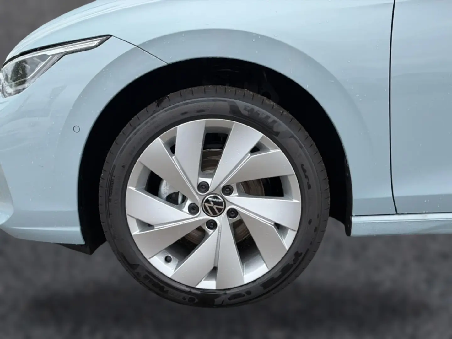 Gros plan sur la roue avant gauche d’une Volkswagen Golf 2026 bleu glacier avec jante alu 17 pouces.