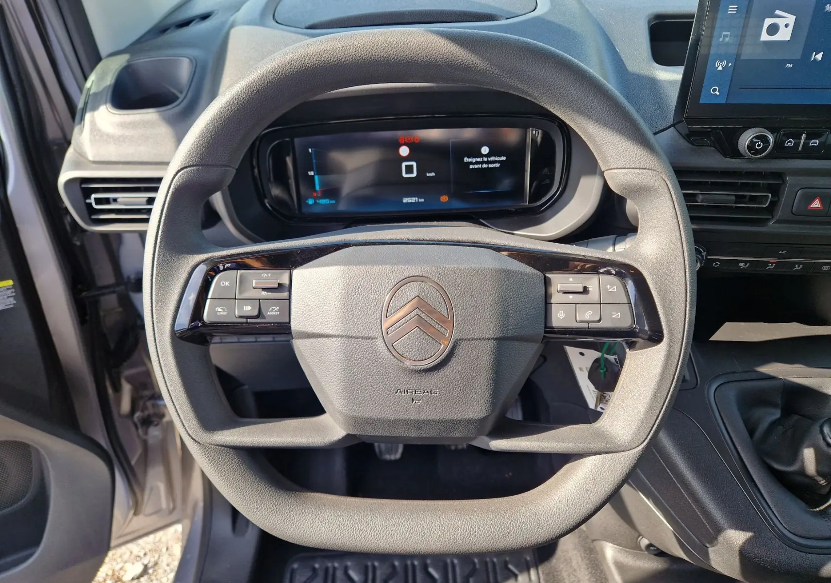 Vue rapprochée du volant gris du Citroën Berlingo 2025 avec commandes intégrées et tableau de bord numérique.