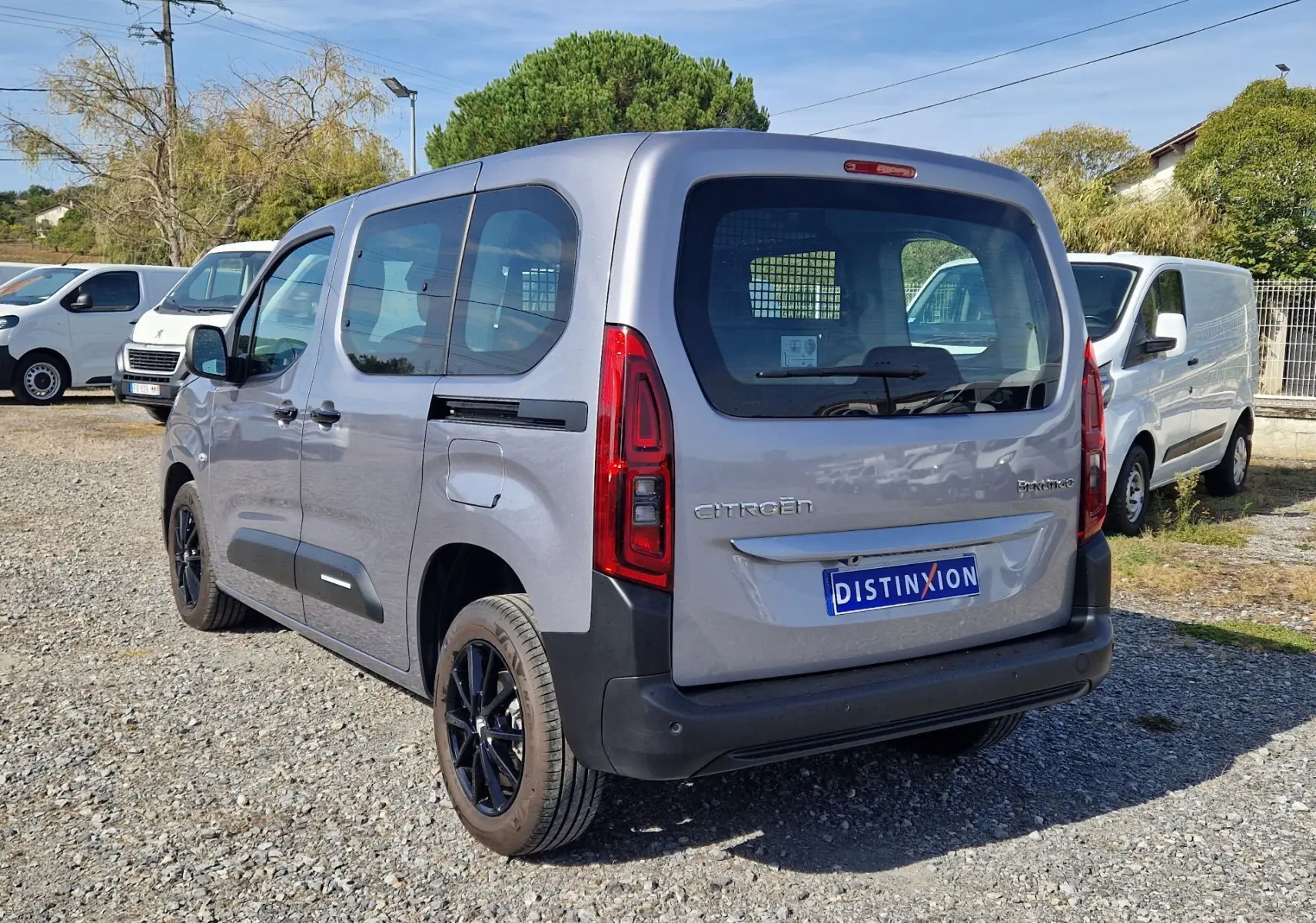 Vue 3/4 arrière droite d'un Citroën Berlingo gris Artense 2025 avec jantes noires et grille de séparation visible à l'arrière.