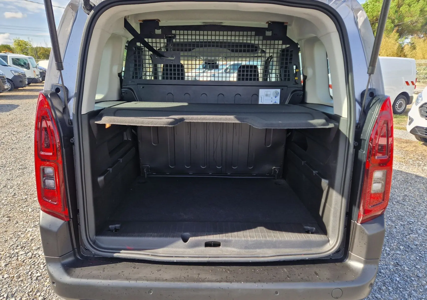 Vue arrière du Citroën Berlingo gris Artense 2025 avec coffre ouvert et grille de séparation visible.