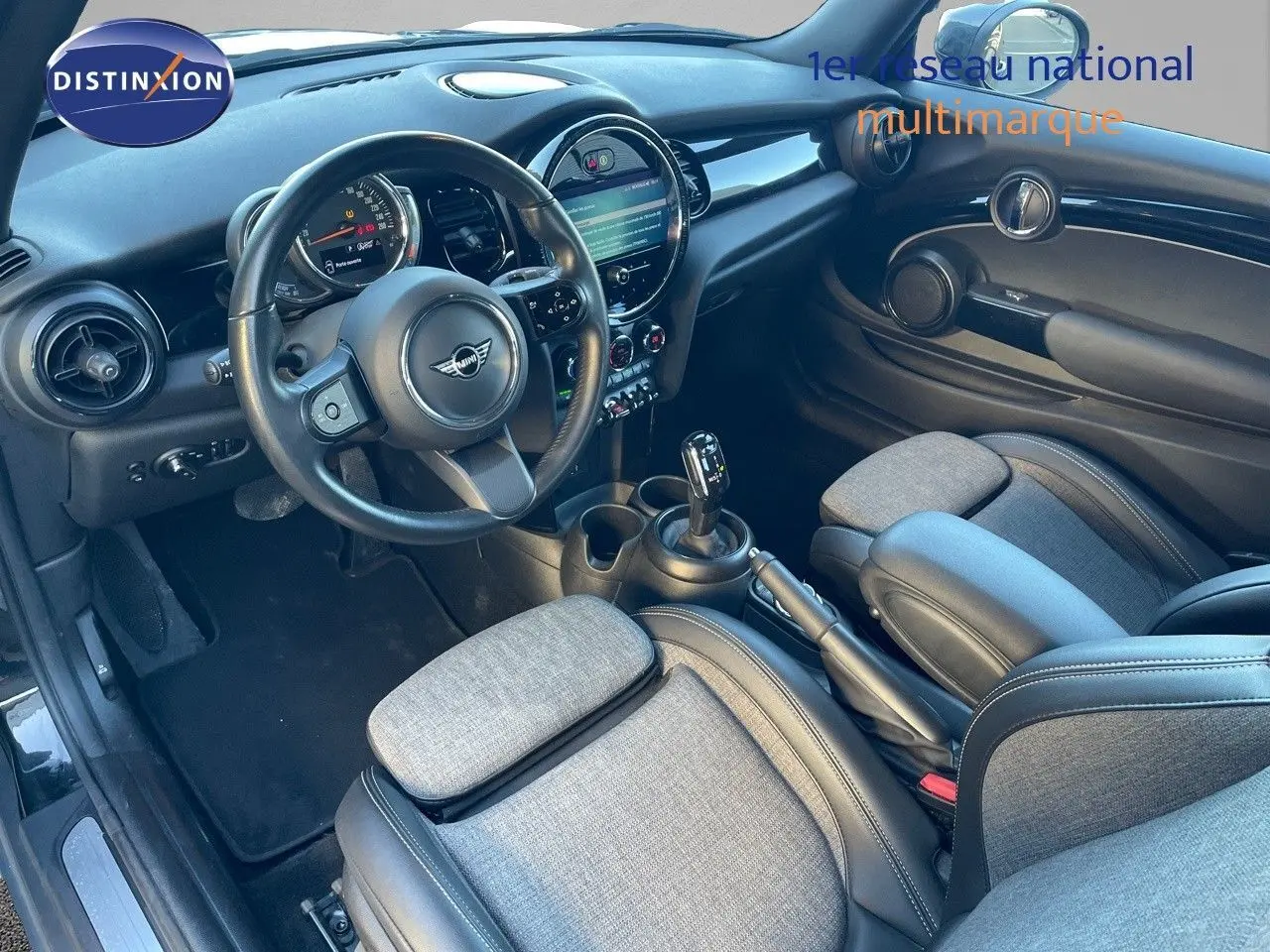 Intérieur avant droit de MINI Cabriolet noir 2023, volant cuir, tableau de bord moderne et sièges tissu gris.