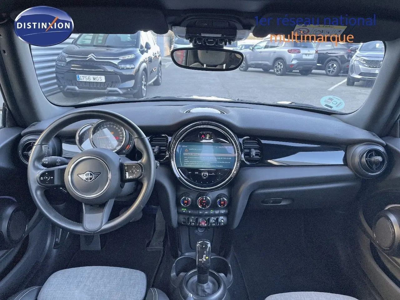 Intérieur de la MINI Cabriolet F57 2023 noir, vue frontale sur le tableau de bord et volant avec écran central rond.
