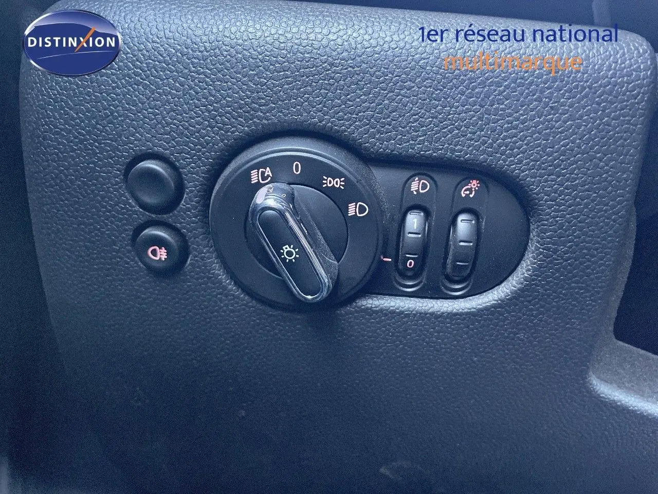 Gros plan sur les commandes d'éclairage du tableau de bord d'une MINI Cabriolet F57 noire, avec interrupteurs et réglages visibles.