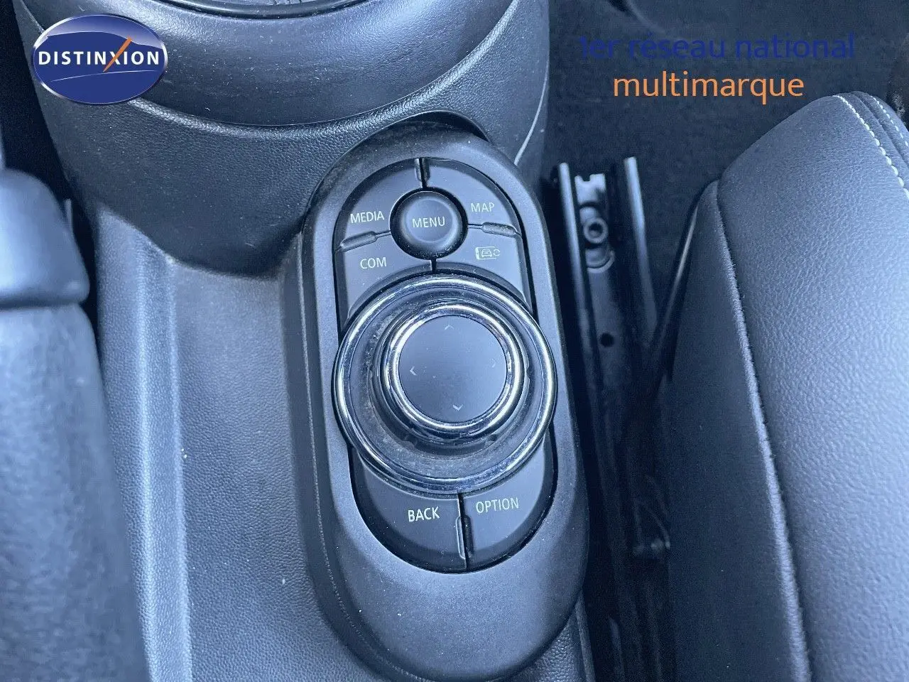 Gros plan sur la molette de commande multimédia au centre de la console d'une MINI Cabriolet noire.