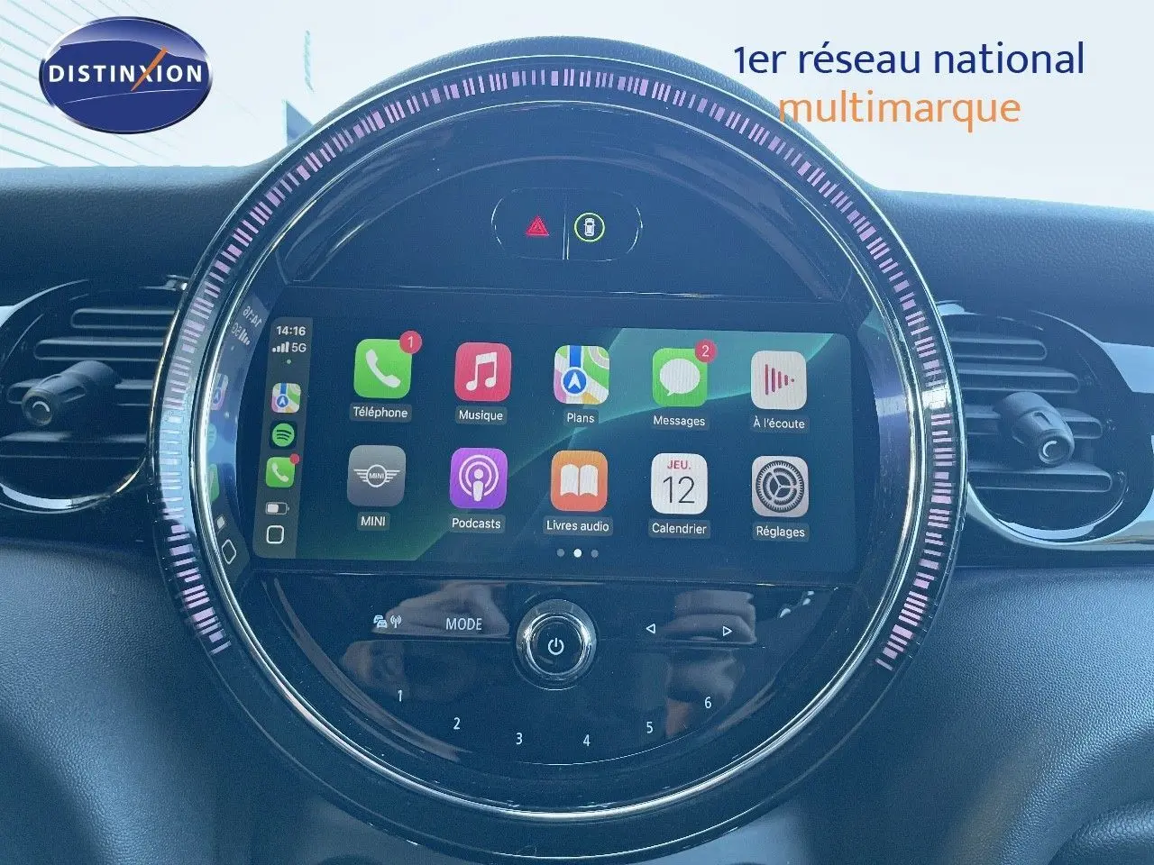 Gros plan sur l'écran tactile central rond du tableau de bord d'une MINI Cabriolet noire, affichant des applications connectées.