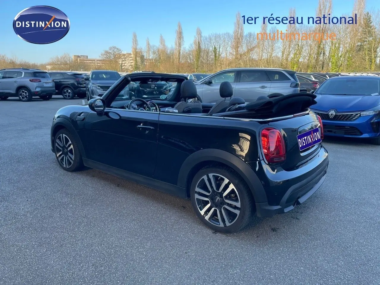 MINI Cabriolet noir Midnight Metal vue 3/4 arrière droit avec capote ouverte sur parking extérieur.