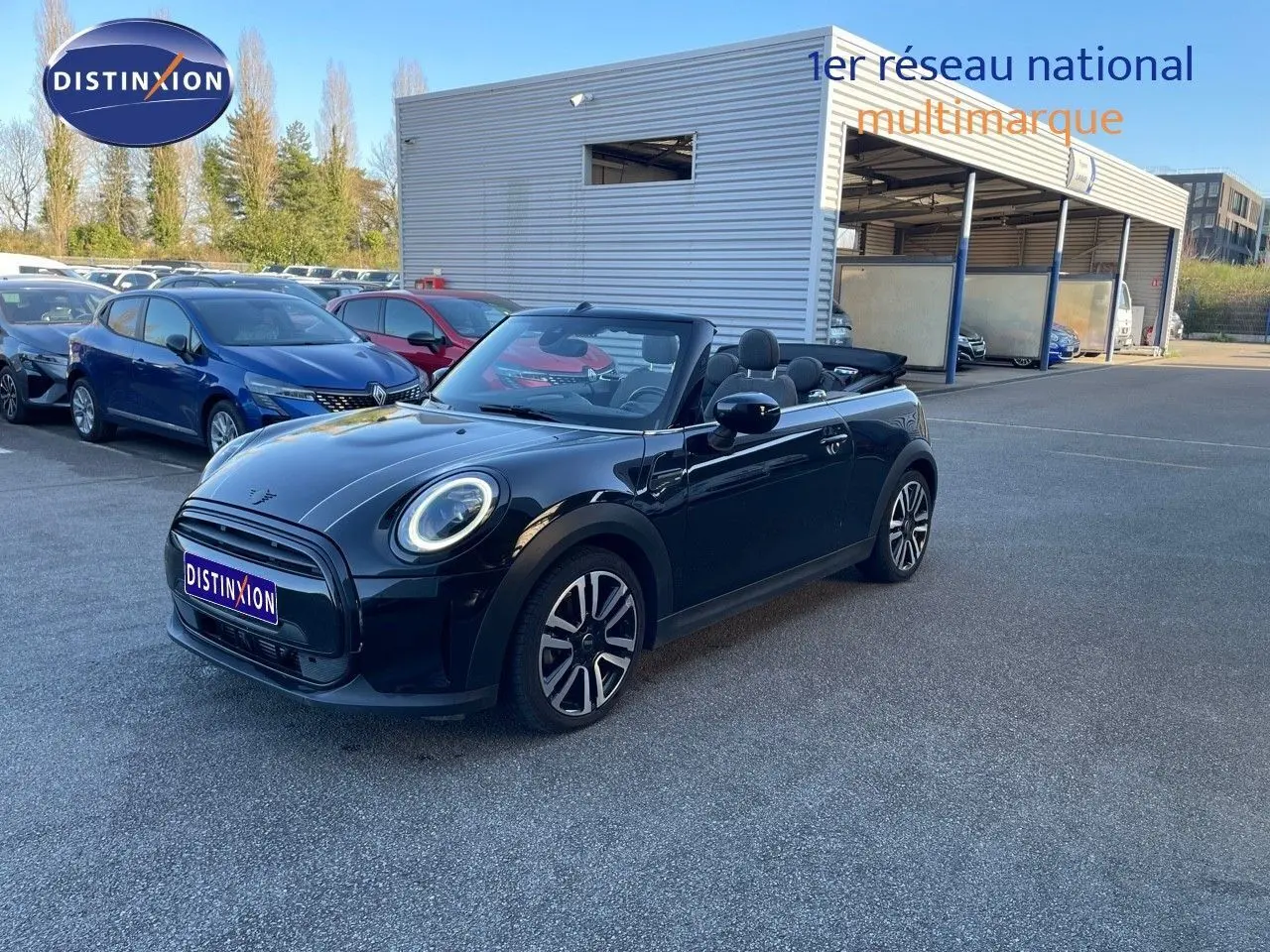 Mini Cabriolet noir Midnight Metal vue 3/4 avant droit avec capote ouverte sur parking extérieur