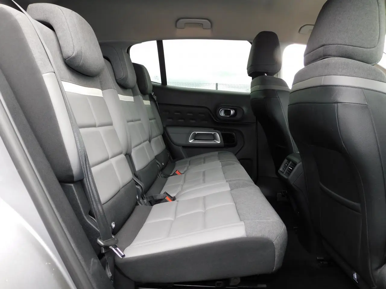 Vue latérale intérieure des sièges arrière gris clair et foncé du Citroën C5 Aircross 2020 avec appuie-têtes et ceintures visibles.