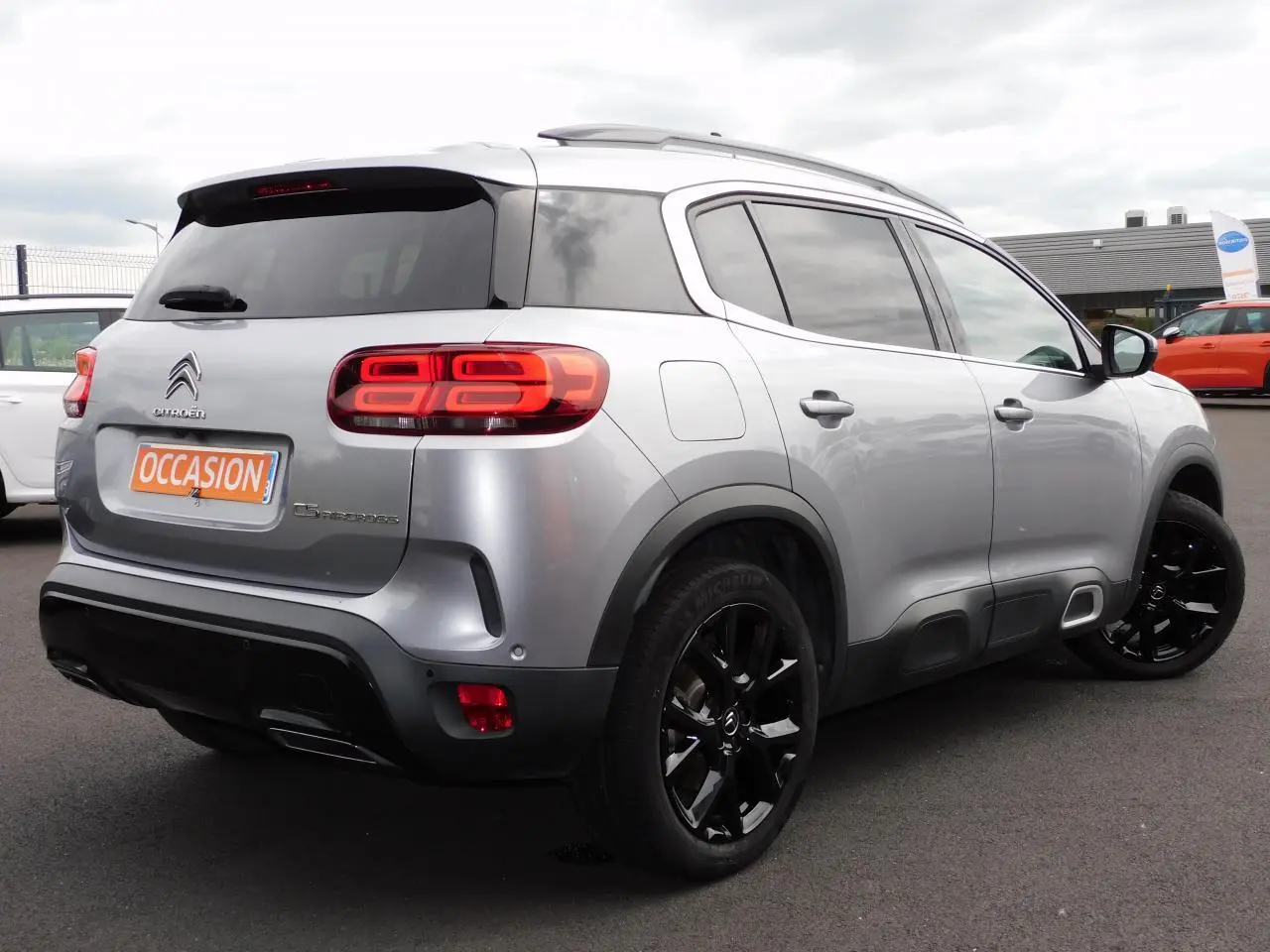 Vue 3/4 arrière droit d'un Citroën C5 Aircross gris avec jantes noires et feux arrière LED distinctifs.