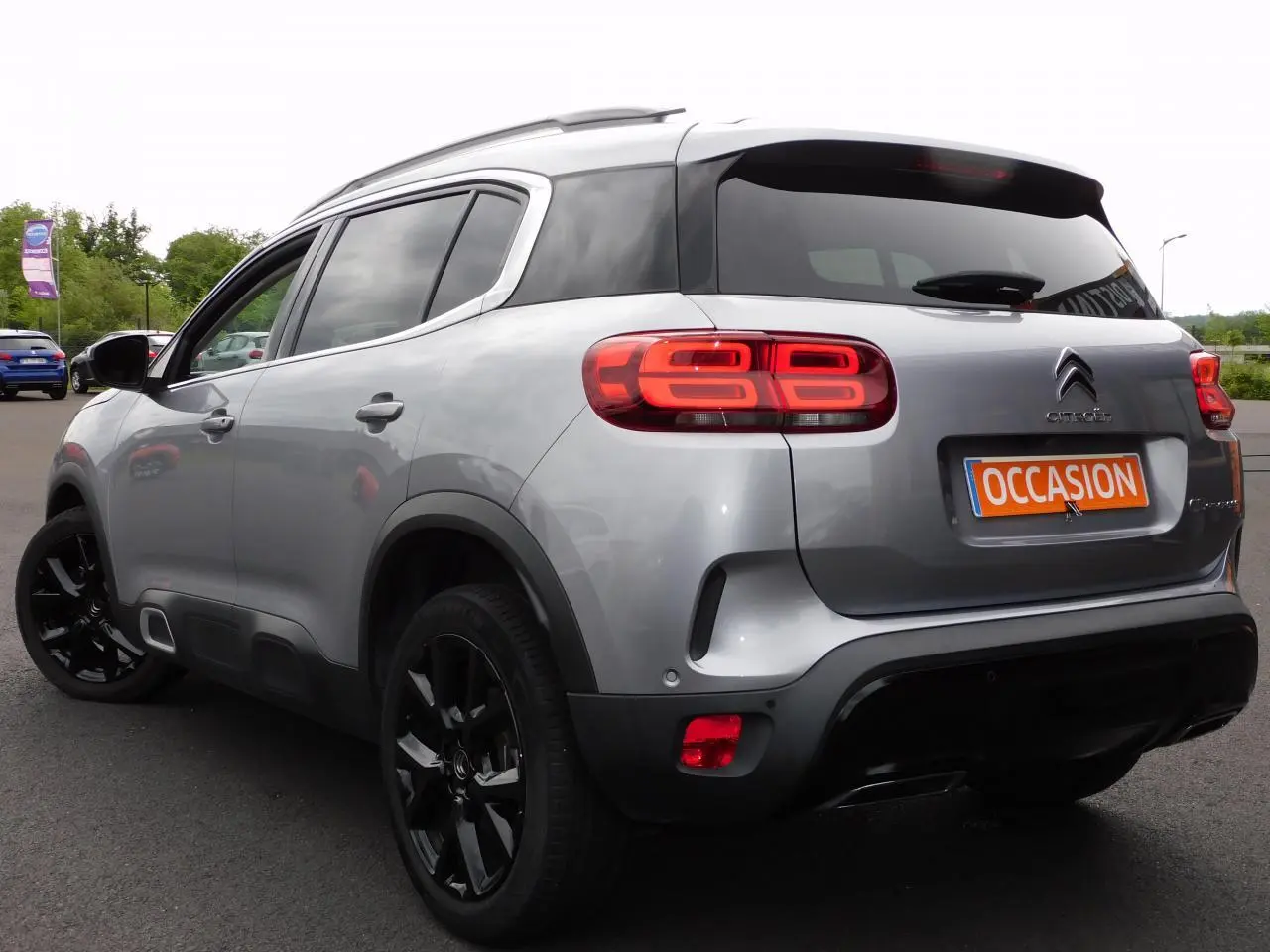 Vue 3/4 arrière droite d'un Citroën C5 Aircross gris avec feux arrière LED et jantes alliage noires.