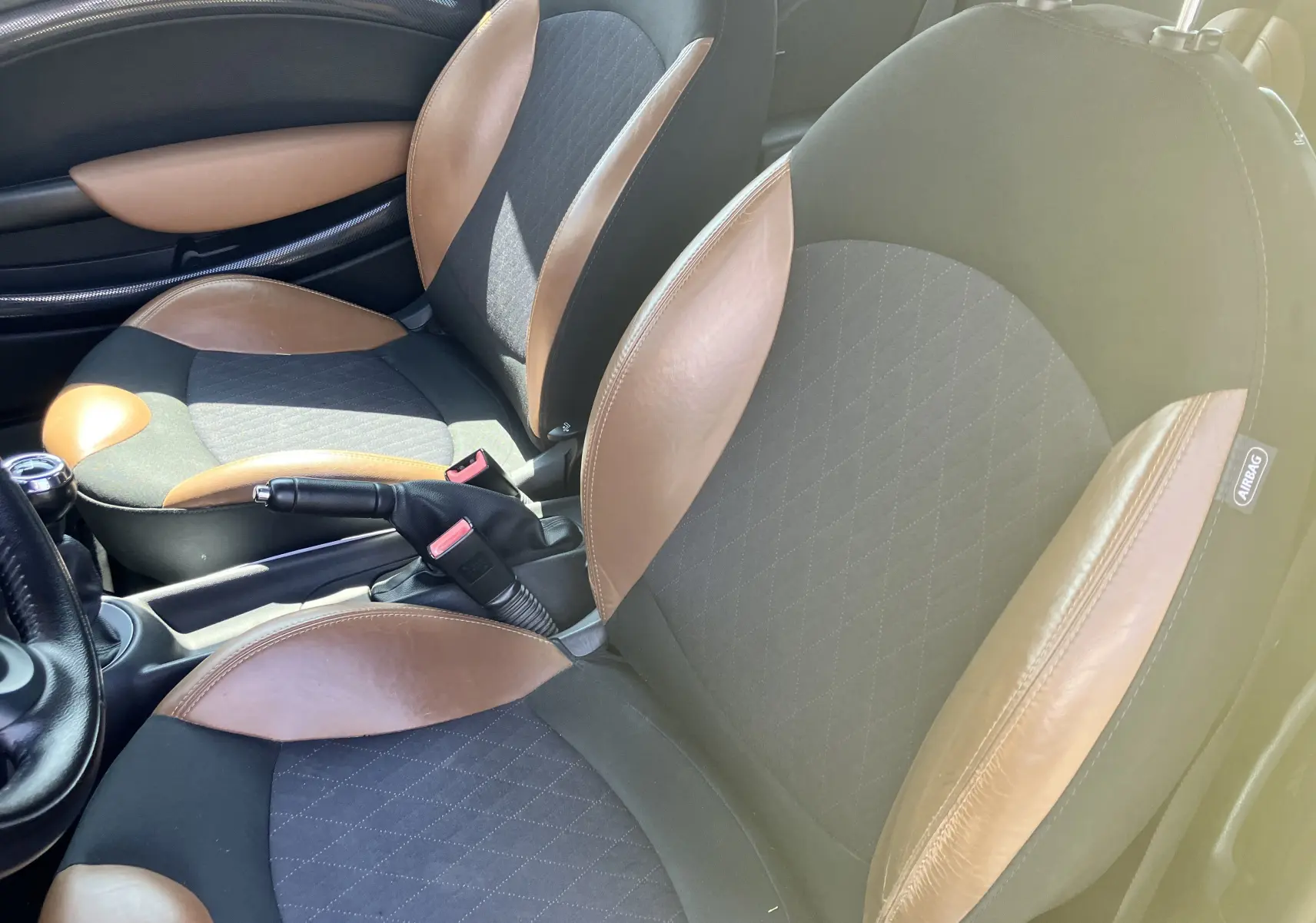 Vue rapprochée des sièges avant marron et noir en tissu et cuir dans l'habitacle d'une MINI Cooper S R56 de 2012.