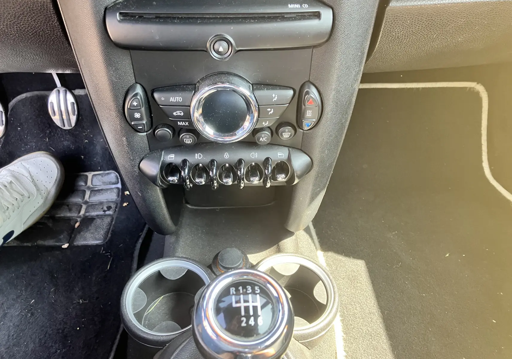 Vue rapprochée de la console centrale et levier de vitesse manuel d'une MINI Cooper marron de 2012.