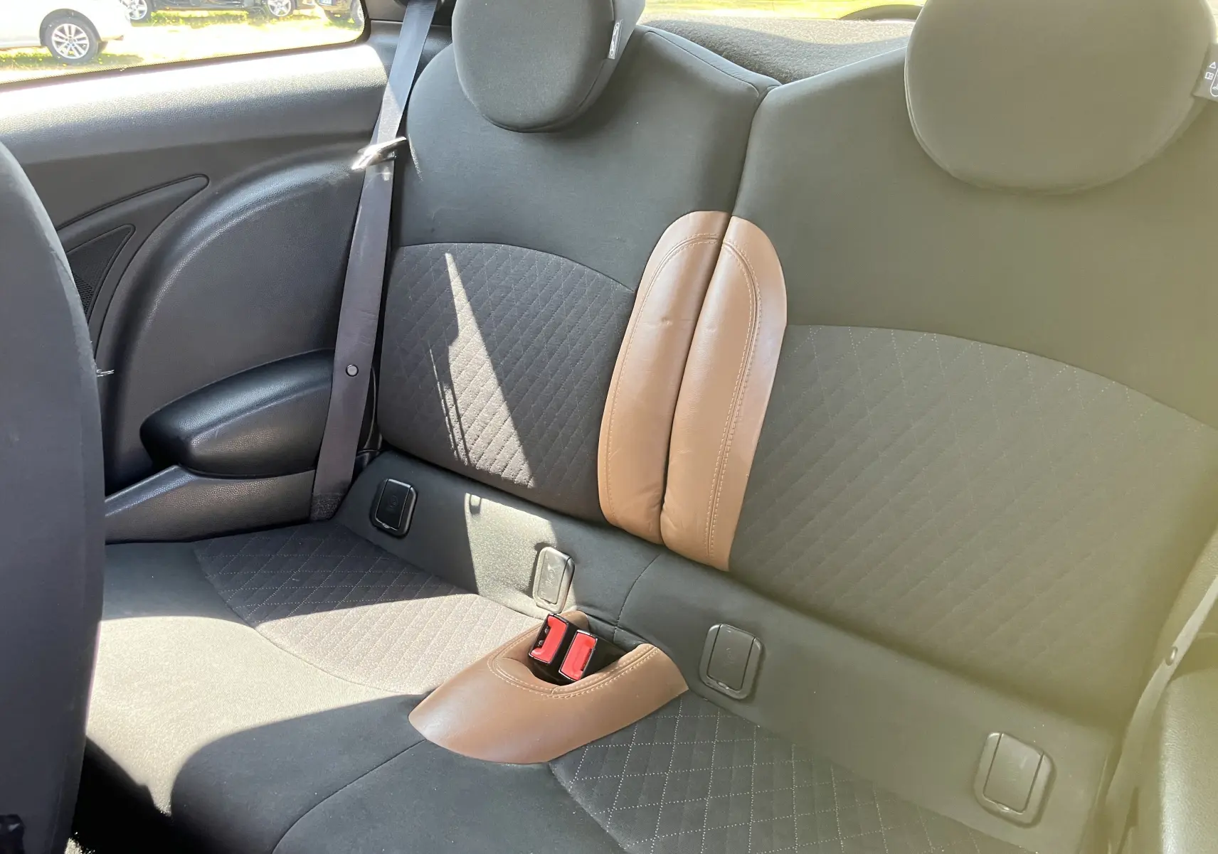 Vue intérieure de l'arrière de la MINI Cooper S R56 2012, sièges noirs avec inserts marron et ceinture de sécurité visible.