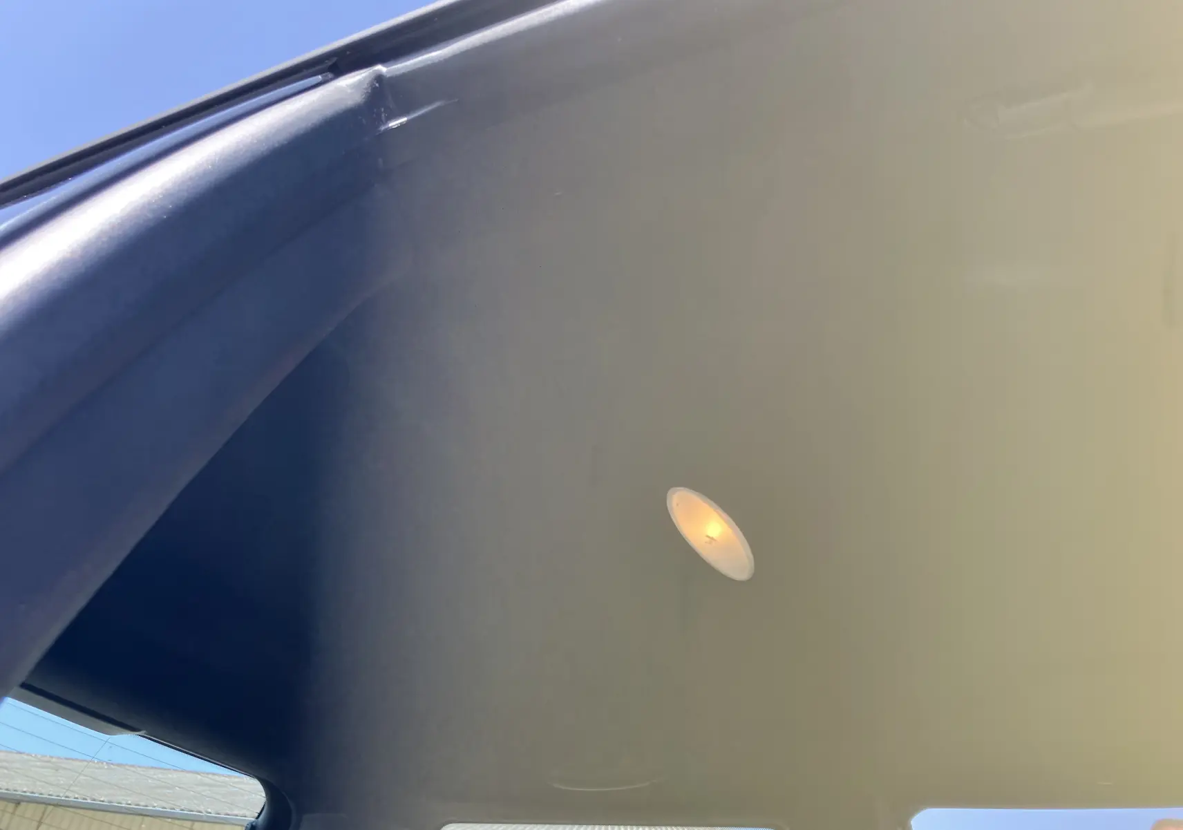 Vue intérieure du toit noir éclairé d'une MINI Cooper S R56 marron, avec lumière de plafond allumée visible.