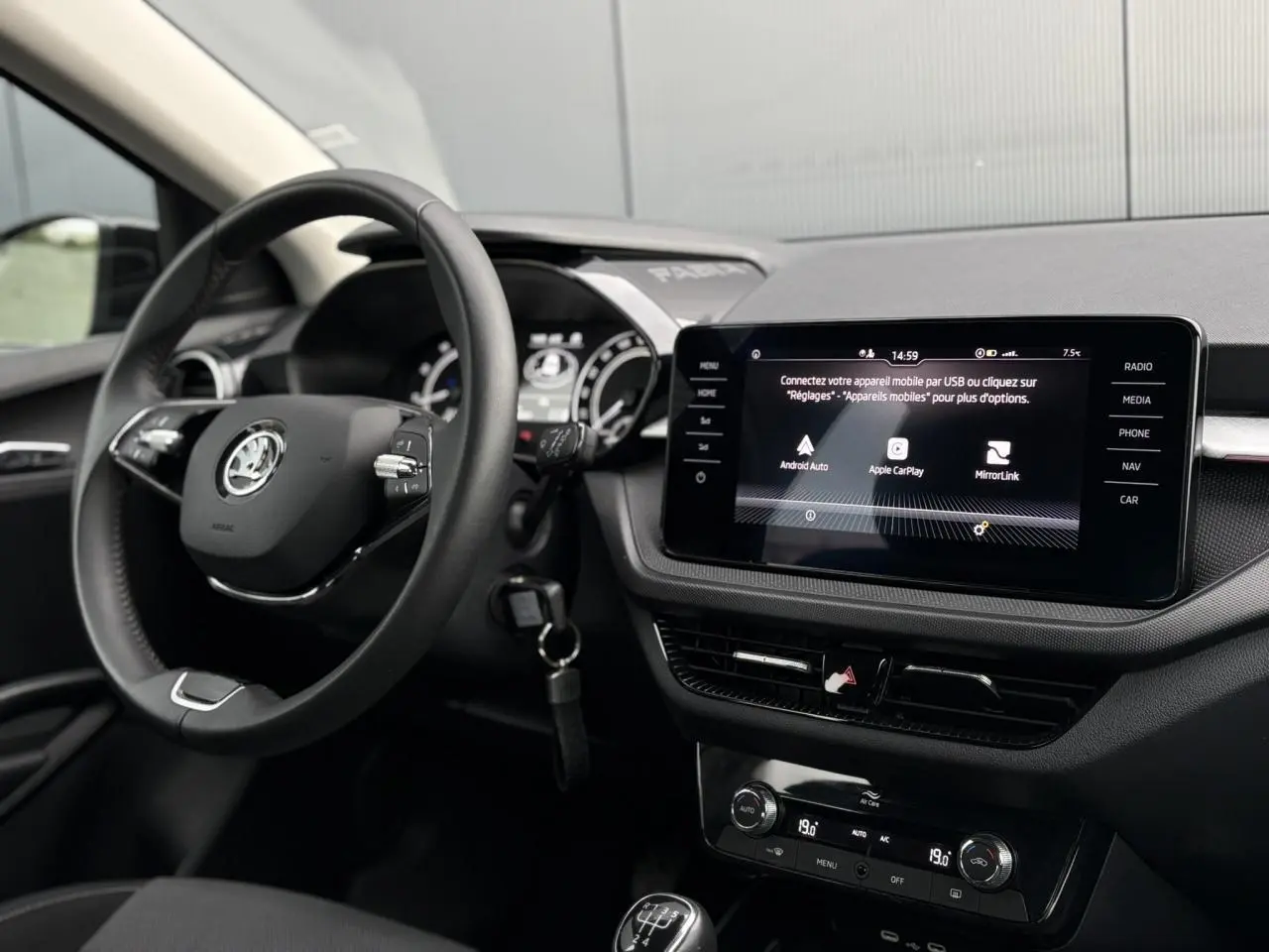 Vue intérieure côté conducteur de la Skoda Fabia 2024 noire Magic, siège tissu avec réglage lombaire manuel visible.