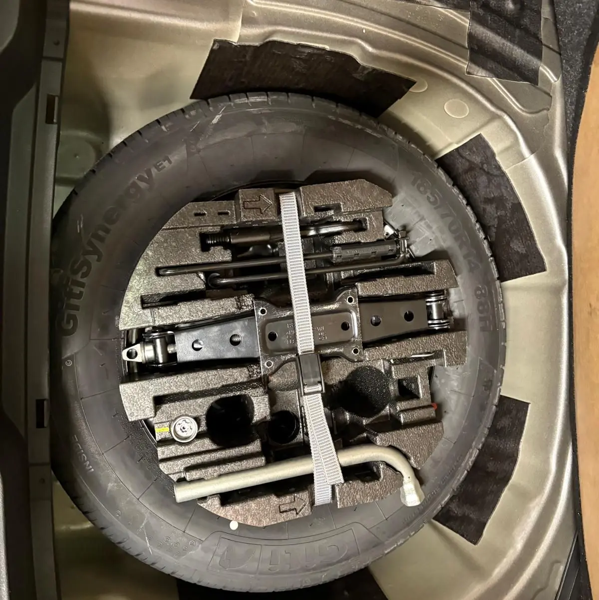 Gros plan sur la roue de secours et les outils de bord dans le coffre de la Skoda Fabia 2023 Gris Graphite.