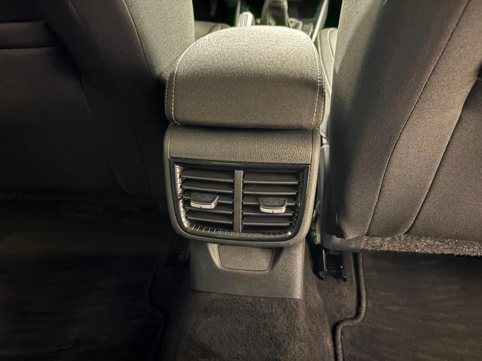 Vue intérieure arrière centrée sur la console de ventilation entre les sièges avant d’une Skoda Fabia gris graphite 2023.