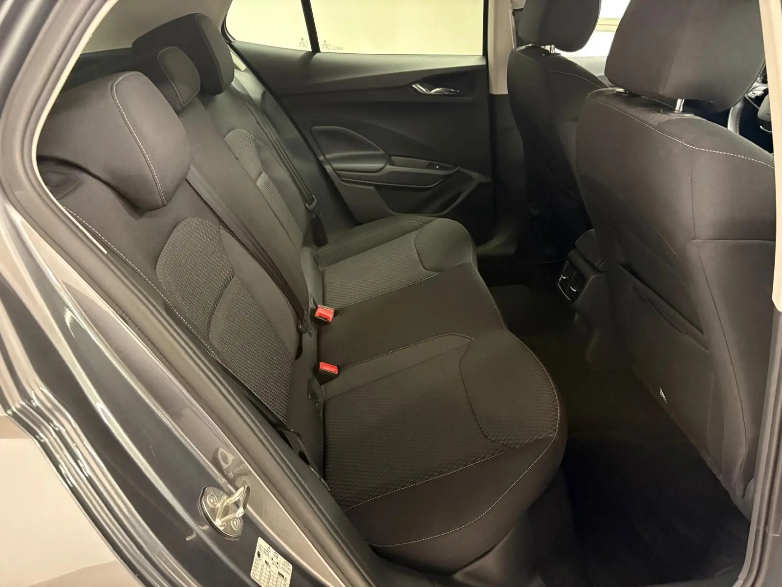 Vue intérieure sur les sièges arrière noirs d’une Skoda Fabia 2023, porte ouverte côté gauche, tissu avec surpiqûres visibles.