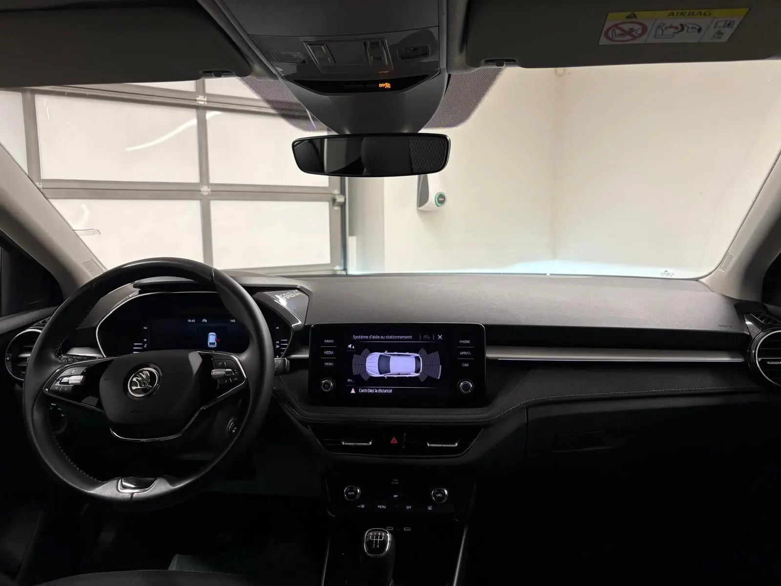 Intérieur de la Skoda Fabia 2023 gris graphite vu de face, tableau de bord avec écran tactile et volant multifonction.