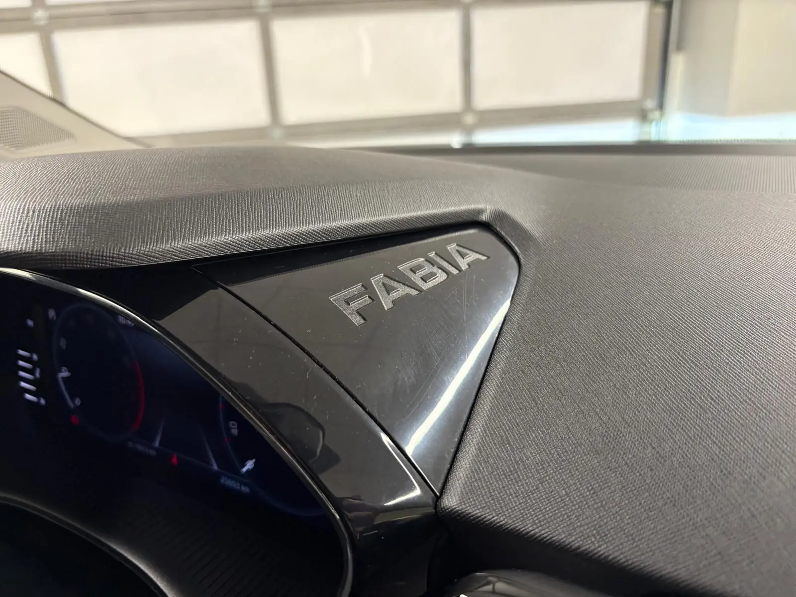 Gros plan sur le tableau de bord noir brillant avec le logo Fabia gravé, intérieur d'une Skoda Fabia 2023.