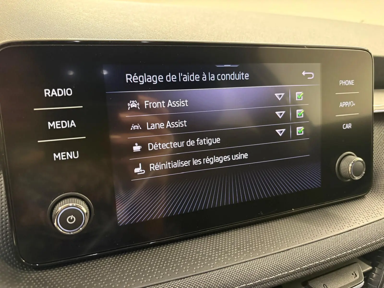 Écran tactile intérieur du Skoda Fabia 2023 affichant les réglages d’aide à la conduite, vue de face.