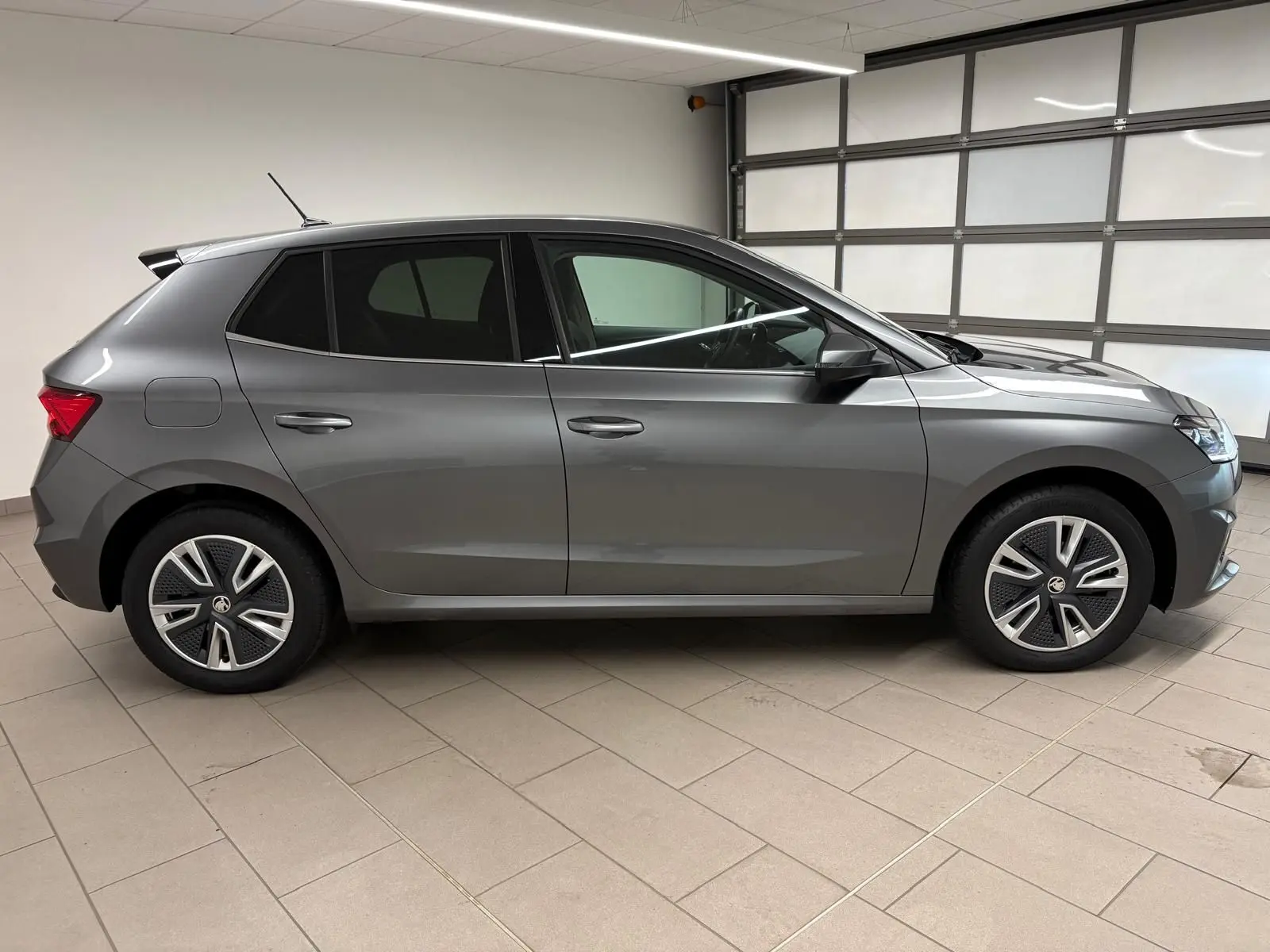 Vue de profil côté gauche d'une Skoda Fabia 2023 gris graphite métallisé avec jantes spécifiques et antenne sur le toit.