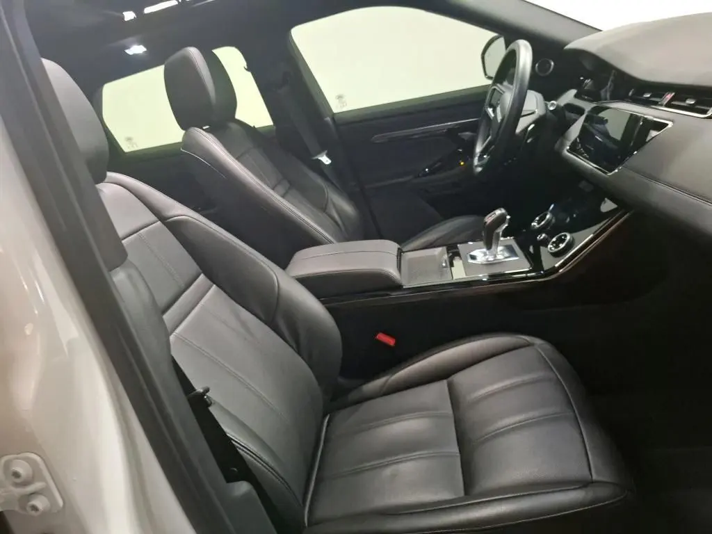 Vue intérieure côté conducteur du Range Rover Evoque 2022, sièges cuir noir et console centrale avec levier de vitesse.