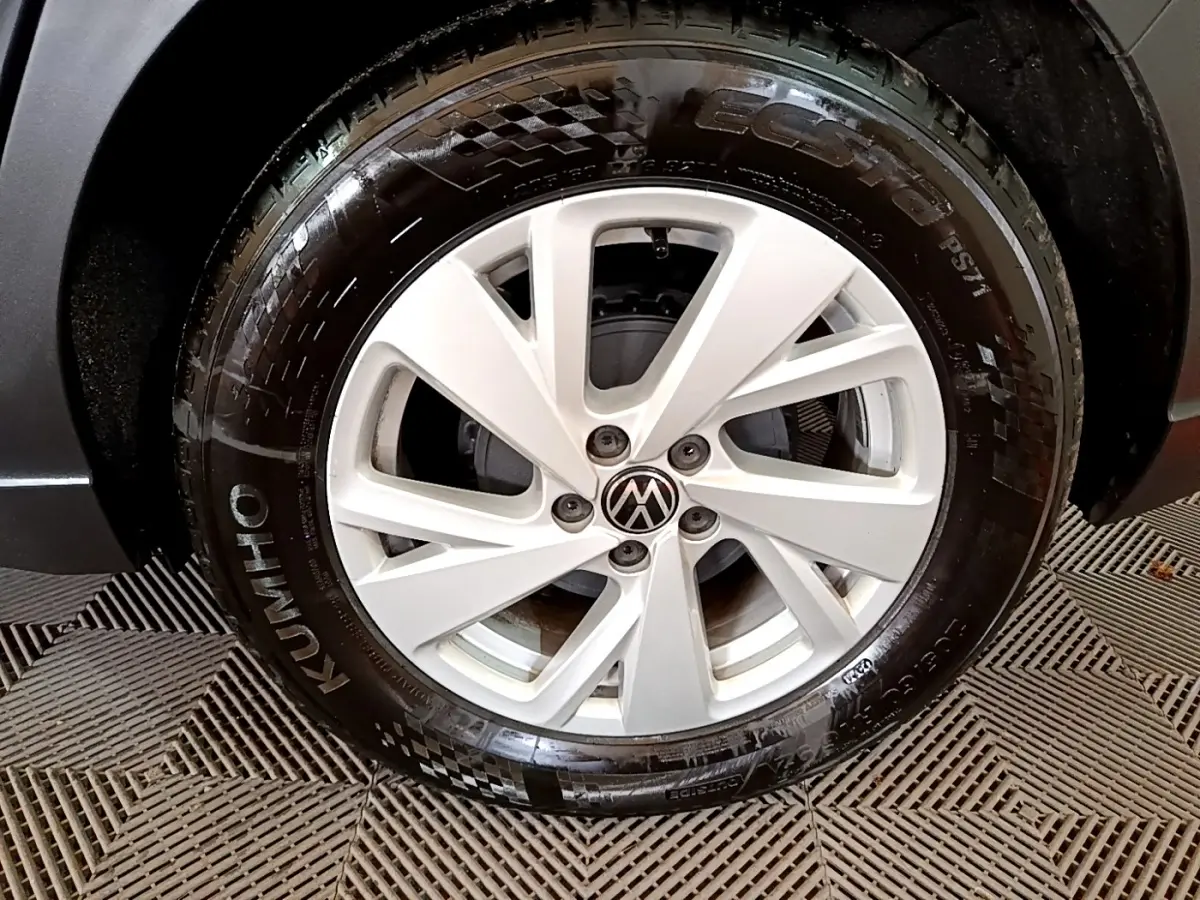 Gros plan sur la roue avant droite du Volkswagen Taigo noir, mettant en valeur la jante alliage et le pneu Kumho.