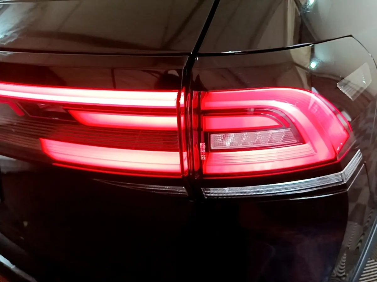 Gros plan sur le feu arrière droit rouge allumé d’un Volkswagen Taigo noir, soulignant ses lignes LED distinctives.