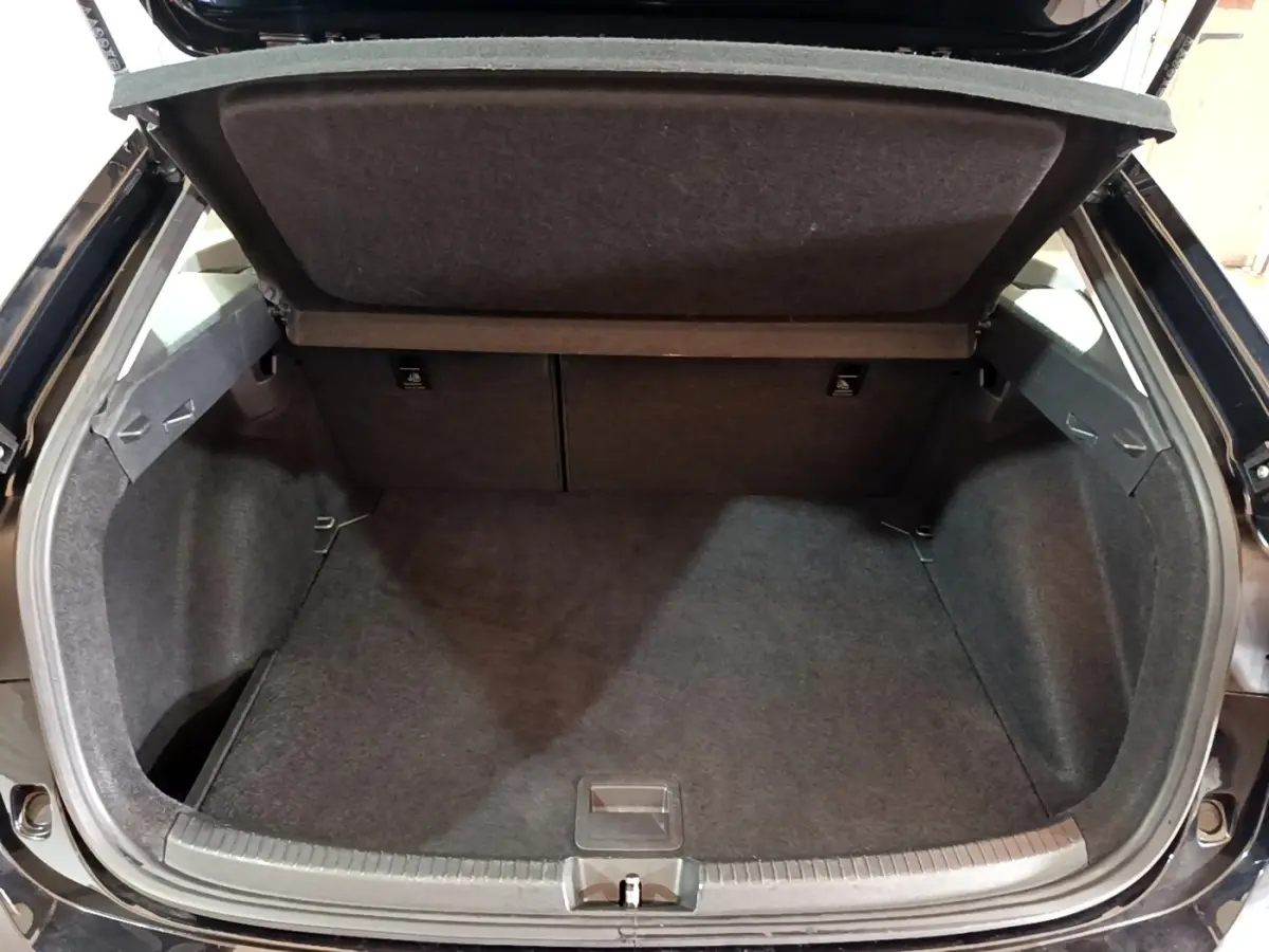 Coffre ouvert vu de l'arrière d'un Volkswagen Taigo noir, montrant l'espace de chargement vide et la tablette de séparation.