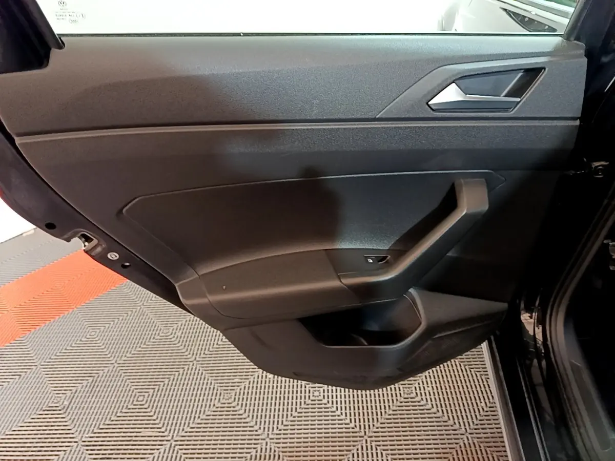 Porte arrière gauche noire de Volkswagen Taigo 2023, intérieur sobre avec poignée angulaire et bouton de lève-vitre.