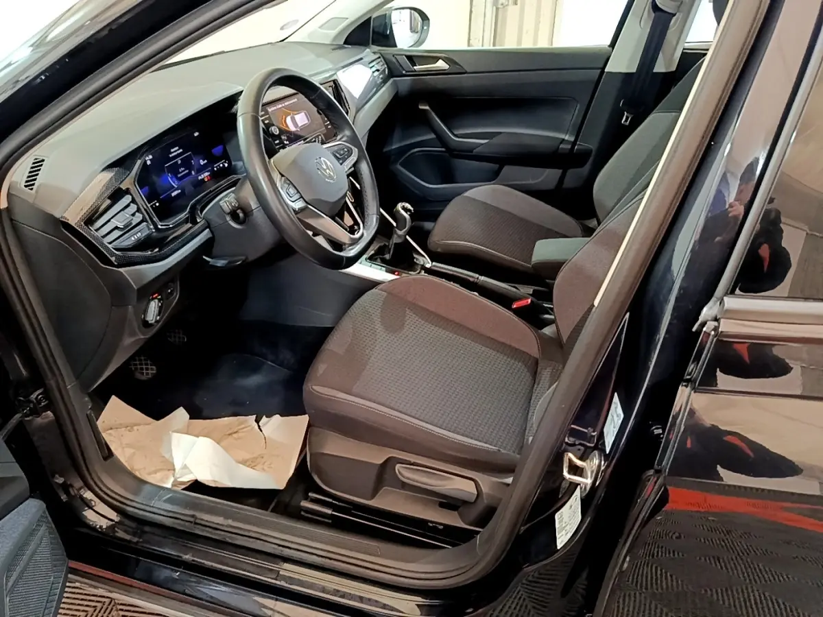 Vue intérieure côté conducteur du Volkswagen Taigo noir 2023, montrant le volant multifonctions et la console centrale.