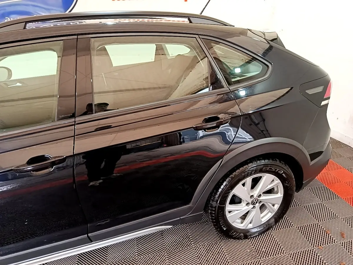 Vue latérale côté droit du Volkswagen Taigo noir 2023, mettant en valeur la porte arrière et la roue arrière.